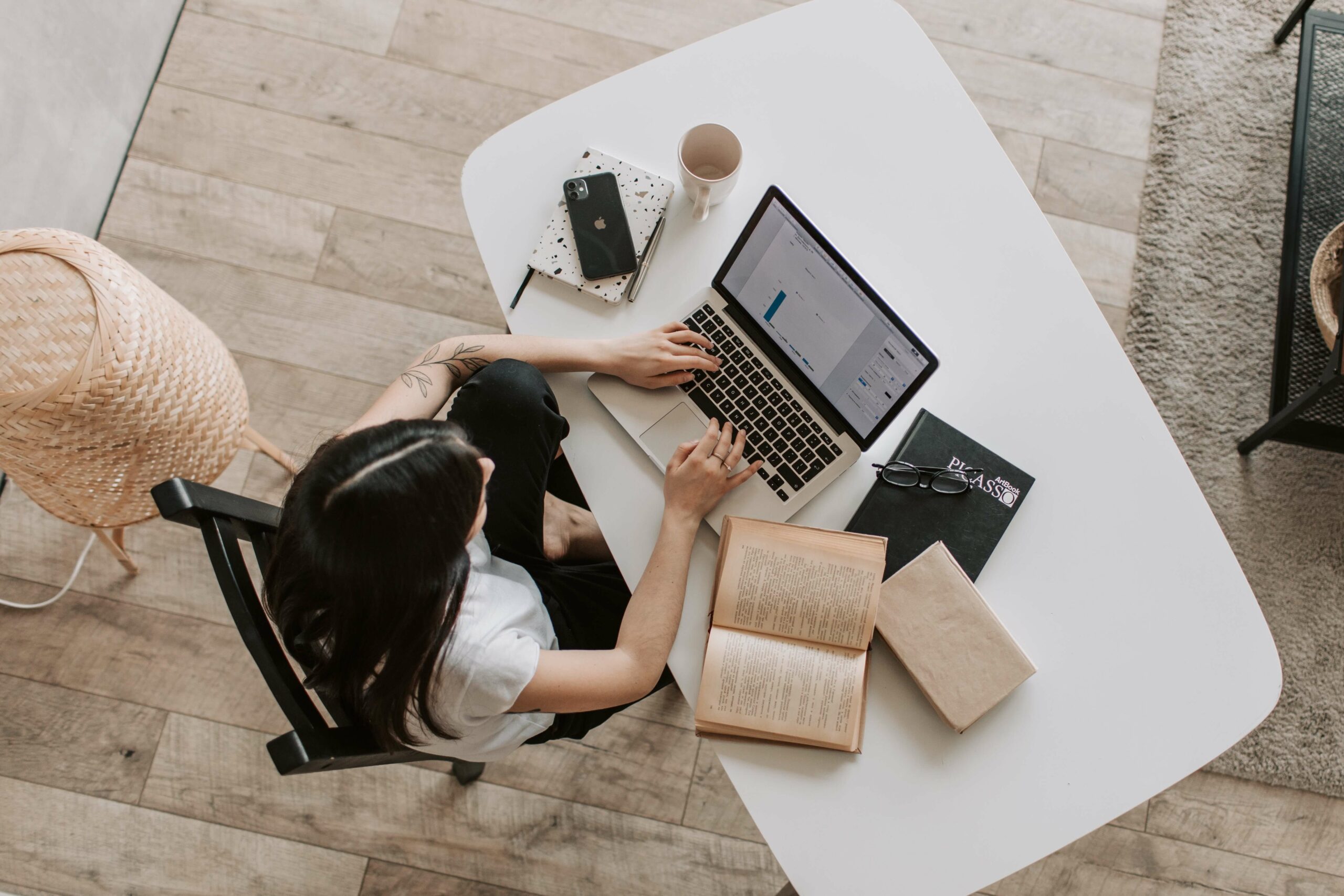 a woman sitting at her desk typing on a laptop.