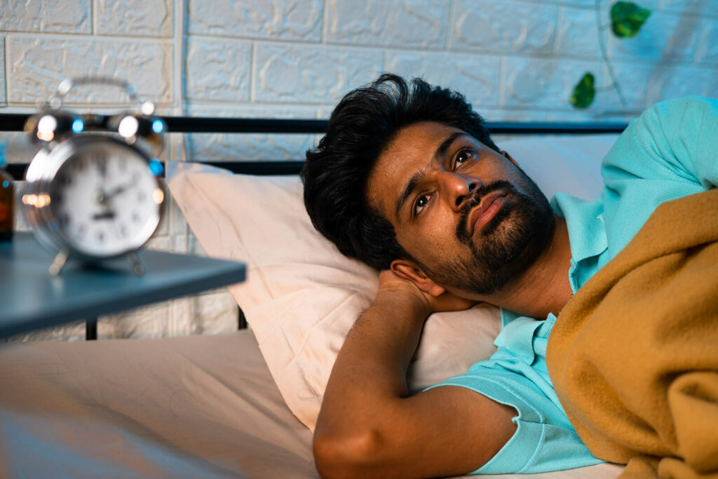 Youn Indian man unable to sleep due to anxious thoughts representing someone in need of Therapy for Anxiety in Washington, DC.
