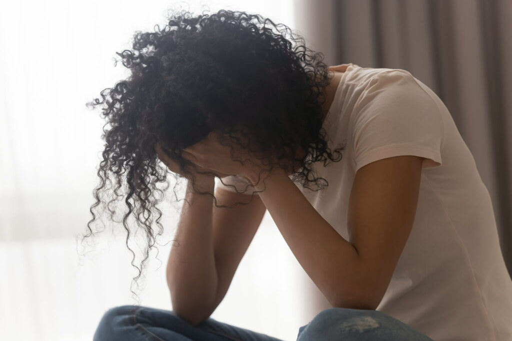 A woman sits with her head in her hands as she battles feelings of anxiety. Working with an Anxiety Therapist in Washington, DC to complete CBT for Anxiety can be hugely beneficial.