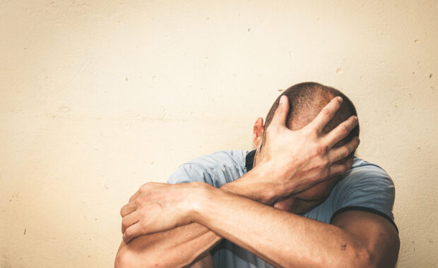 A man leans against a wall overcome by emotion representing someone struggling with depression who could benefit from Therapy for Depression in Washington, DC.