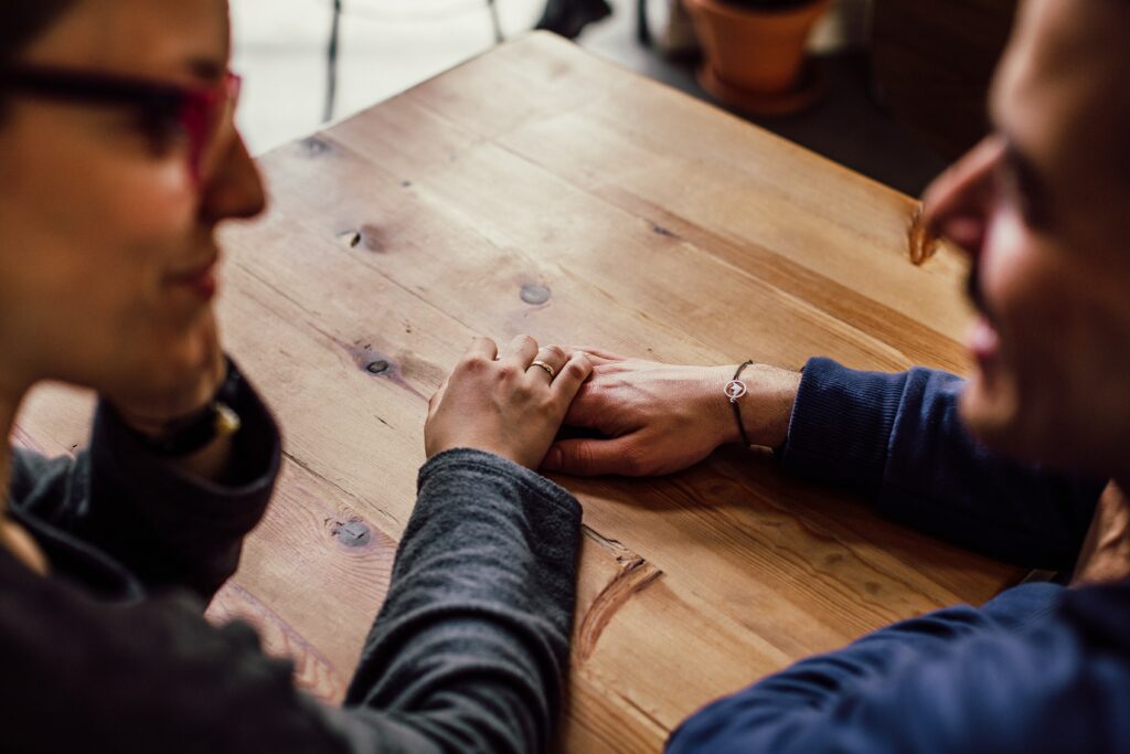 A couple holds hands while deep in conversation. Therapy for Dating Anxiety in Washington, DC can help you up your dating game.
