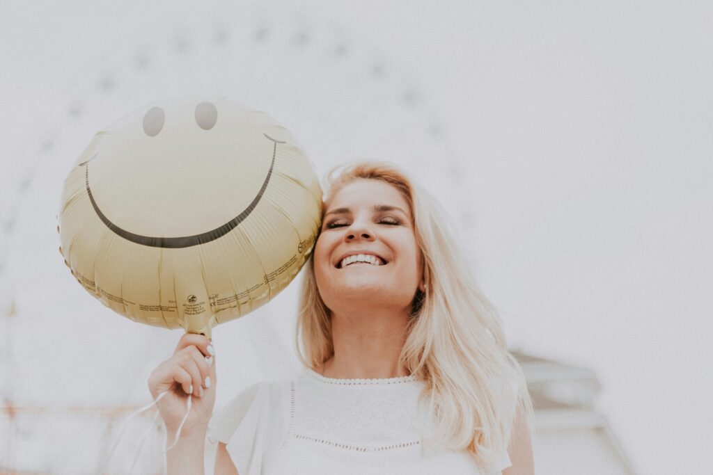 A Happy Woman Holding a Smiley Balloon