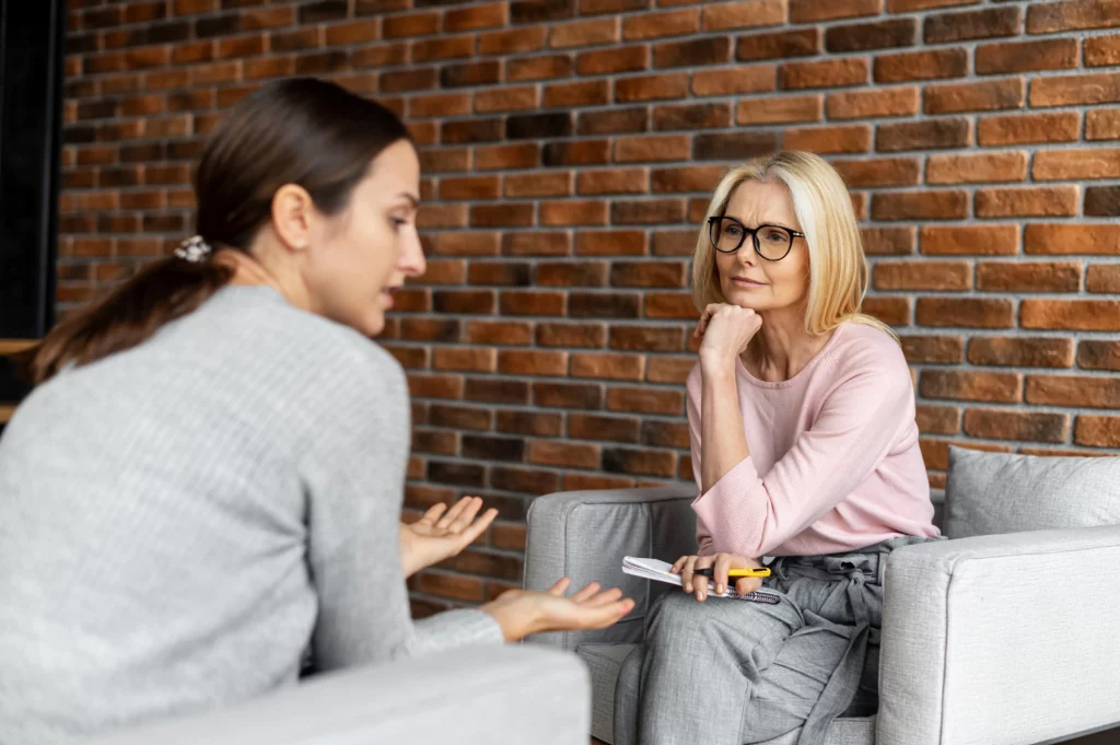 A therapy session with two women. One speaking and the other one listening intently.