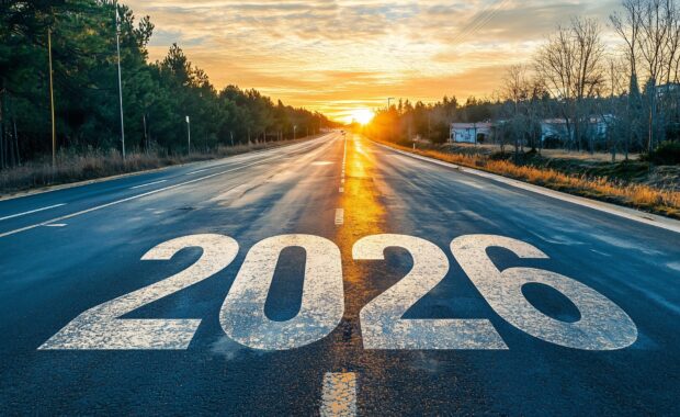Empty highway with large white numbers 2025 painted on asphalt stretching toward bright sunrise on horizon, flanked by trees and power lines, symbolizing new year and fresh start ahead