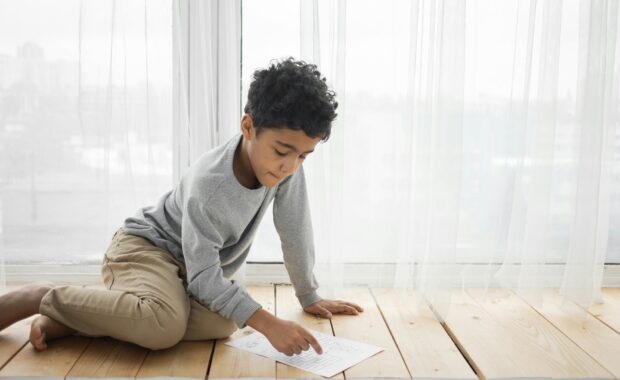A young child sitting on the floor looking at a worksheet, representing child psychological testing and counseling services in Washington DC
